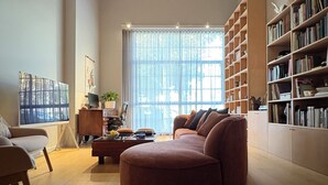 Un salon spacieux avec une grande fenêtre, un canapé confortable, une table basse et une bibliothèque remplie de livres.