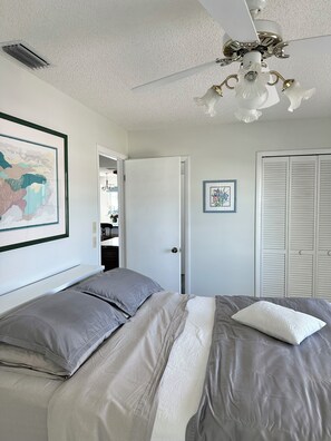 A bedroom with a bed, a ceiling fan, a door, and a closet. - Hammock Beach Cottage (Palm Coast)