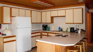 Eine Küche mit Holzschränken, einem weißen Kühlschrank, einer Kaffeemaschine und einem Mixer auf der Arbeitsplatte.