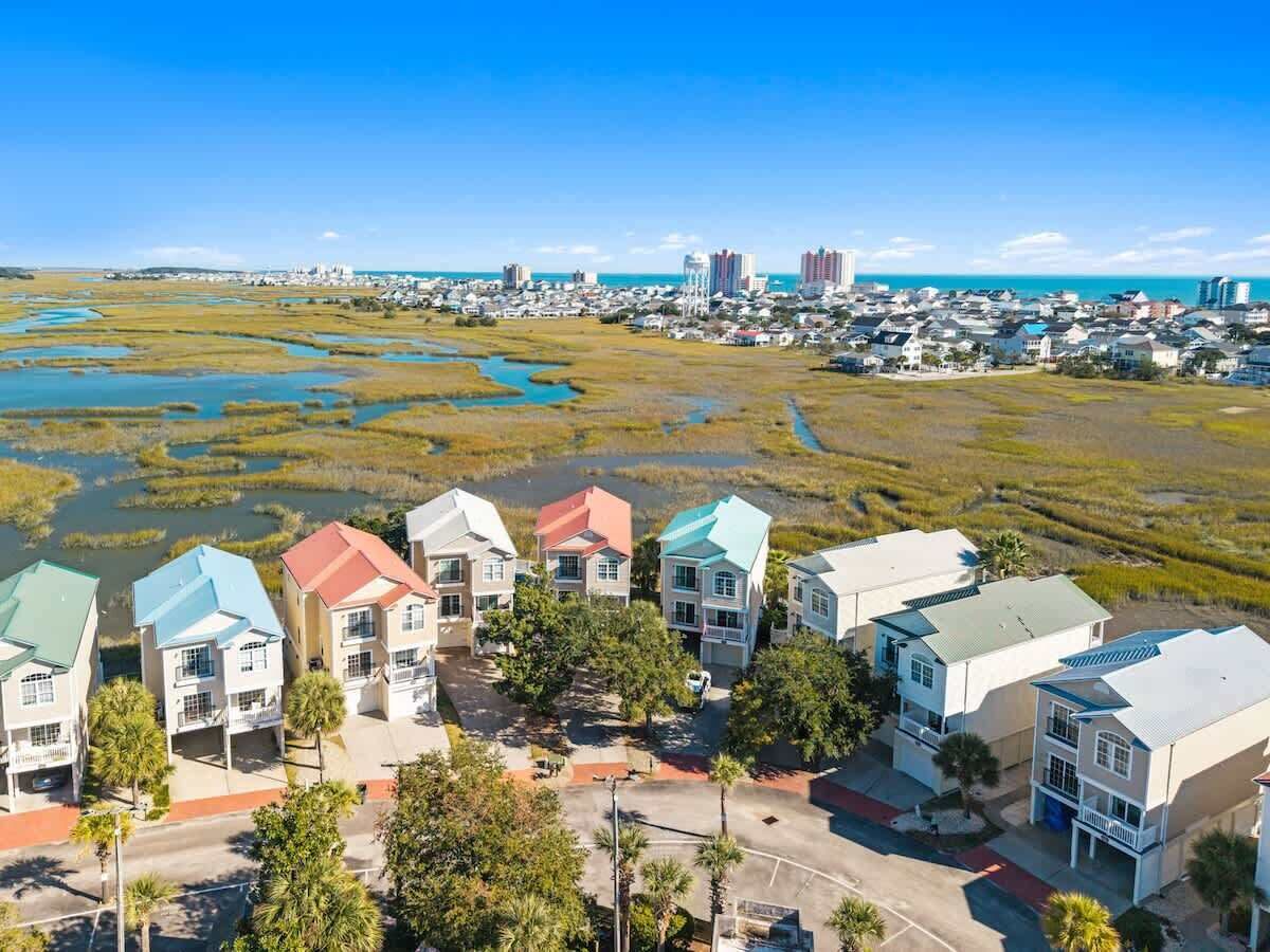 Un quartier résidentiel avec des maisons, une route et une étendue d’eau en arrière-plan.