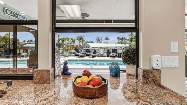 Una cocina con frutero, vista a la piscina y un letrero que indica 'casa de playa'.