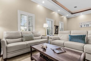 A living room with two beige sofas, a wooden coffee table, and a painting on the wall.