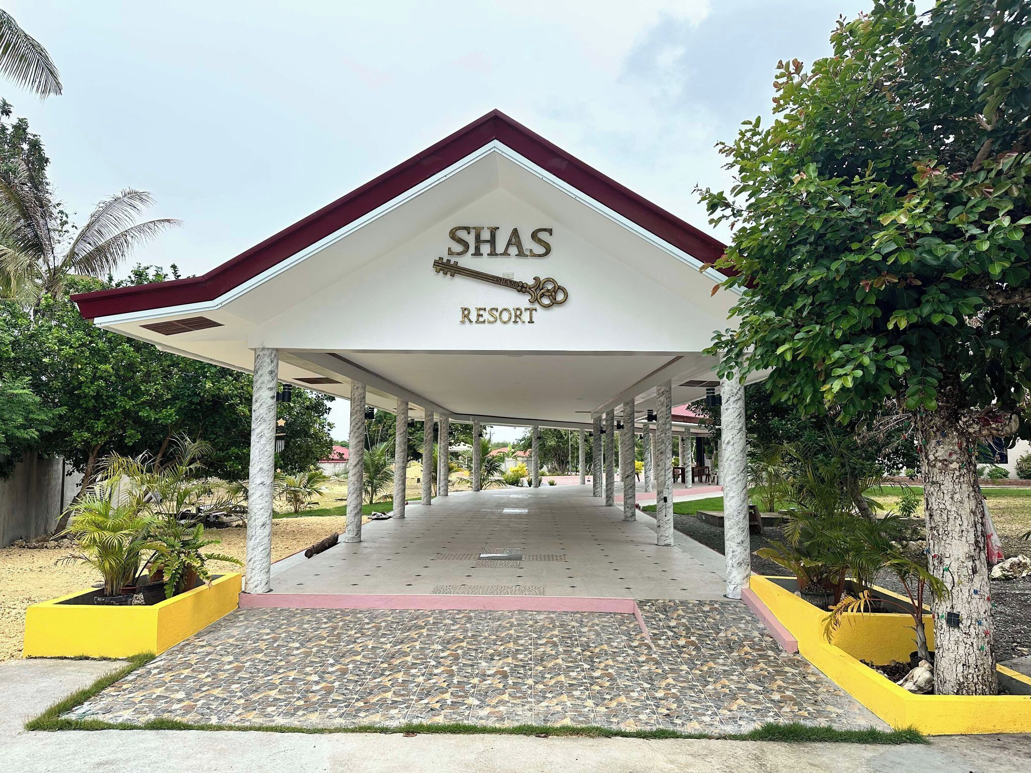 A covered entrance to Shas Resort with a tiled floor and a red roof.