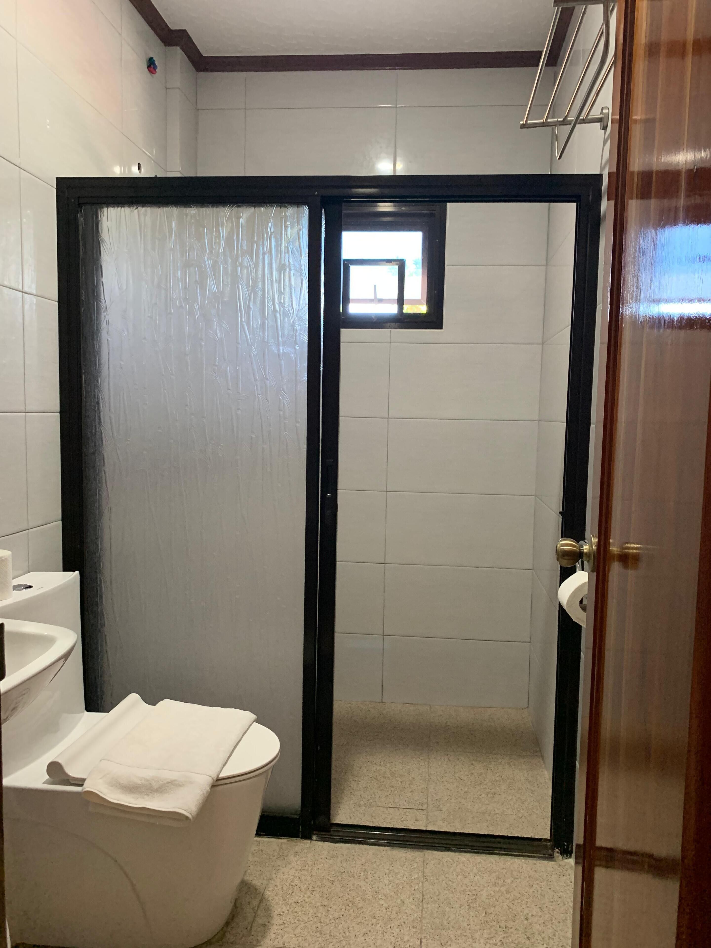 Een badkamer met een wit wastafelmeubel, toilet en douchegedeelte met een zwarte deur.