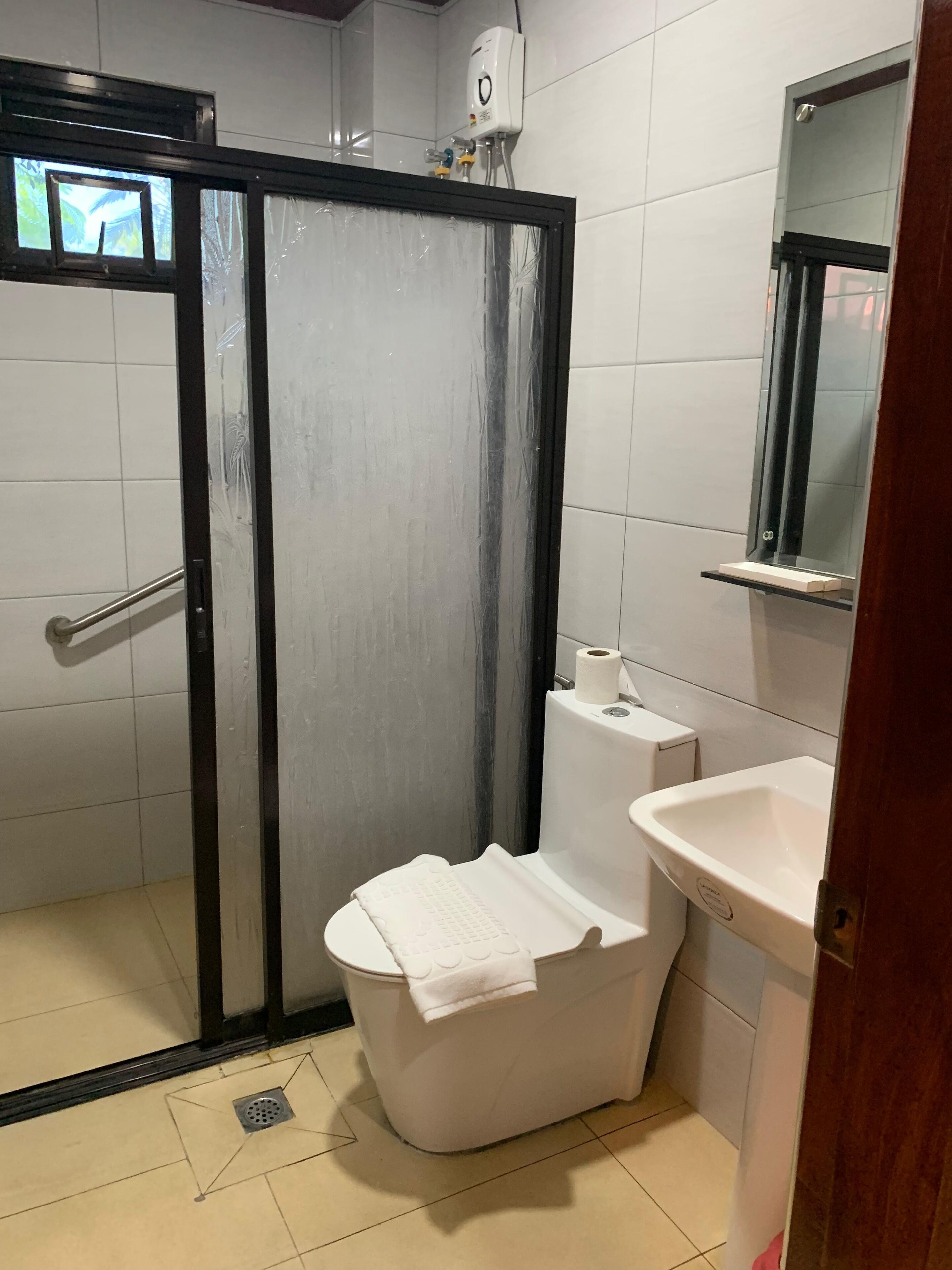 A bathroom with a shower enclosure, toilet, and sink.