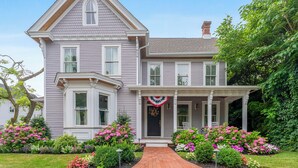A two-story house with a wrap-around porch, a bay window, and a front door with a decorative wreath. - Charming 6-bedroom house with AC, WiFi in wonderful West Cape May (West Cape May)