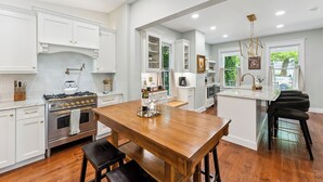 A spacious kitchen with white cabinetry, a wooden dining table, and a central island with stools. - Charming 6-bedroom house with AC, WiFi in wonderful West Cape May (West Cape May)