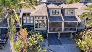 A beachfront property with multiple levels, large windows, and a covered outdoor area.