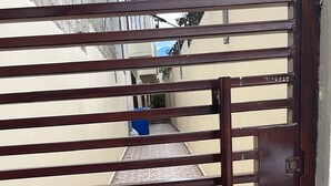 Une porte en métal avec des barreaux horizontaux et une poignée verticale, donnant sur une zone carrelée avec un objet bleu en arrière-plan.