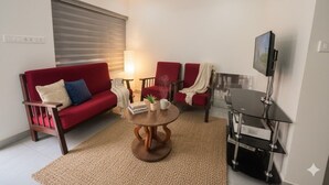 Una sala moderna con un sofá rojo, una mesa de centro y un mueble para televisión.