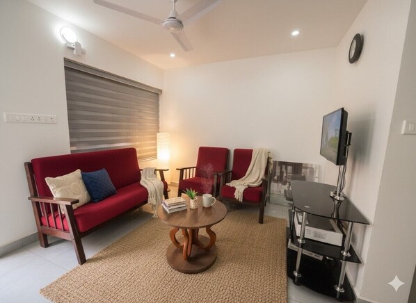 A modern living room with a red sofa, a coffee table, and a TV stand.