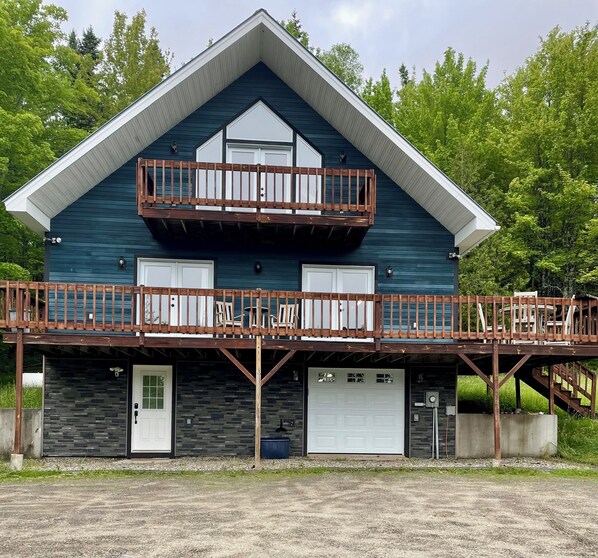 A two-story building with a balcony, a garage, and a stone facade.