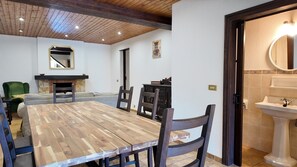 A dining area with a wooden table and chairs, a fireplace, and a mirror on the wall. - Vacation home Pilar (Llanes)