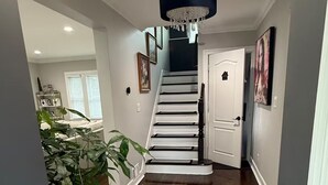 Ein Korridor mit Holzboden, einer Treppe, einer Chandelüster und einem Blumentopf.