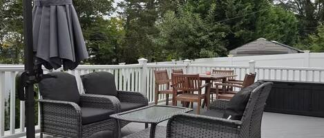 A covered outdoor patio with wicker furniture, a table, and an umbrella.
