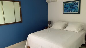 A bedroom with a bed, a nightstand, an air conditioning unit, and a wall-mounted painting.