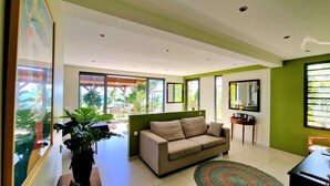 A modern living room with a beige sofa, a coffee table, and a large potted plant.