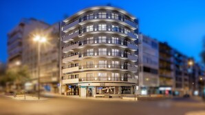 A multi-story hotel with a curved facade, balconies, and a ground-level shop.