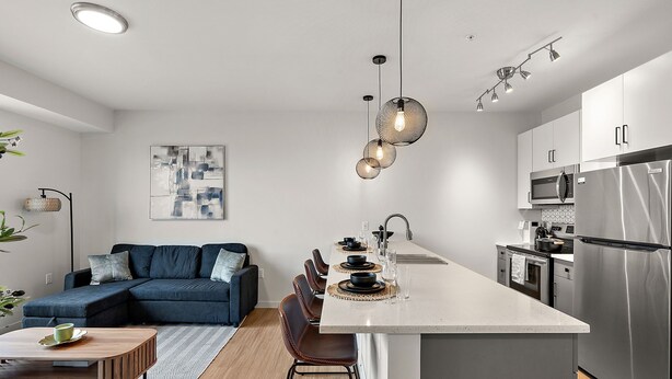 A modern kitchen with a central island, stainless steel appliances, and a dining area with a sofa and chairs. - Luxury 2Bd Condo DT Minneapolis, Minutes From Convention Center & US Bank Arena (Minneapolis)