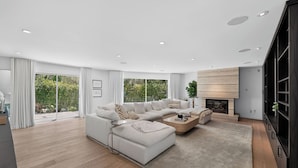 A modern living room with a sectional sofa, a fireplace, and large windows. - Luxury Hollywood Hills Home With Pool, Outdoor Dining & Iconic Views Skyline Chalet (West Hollywood)