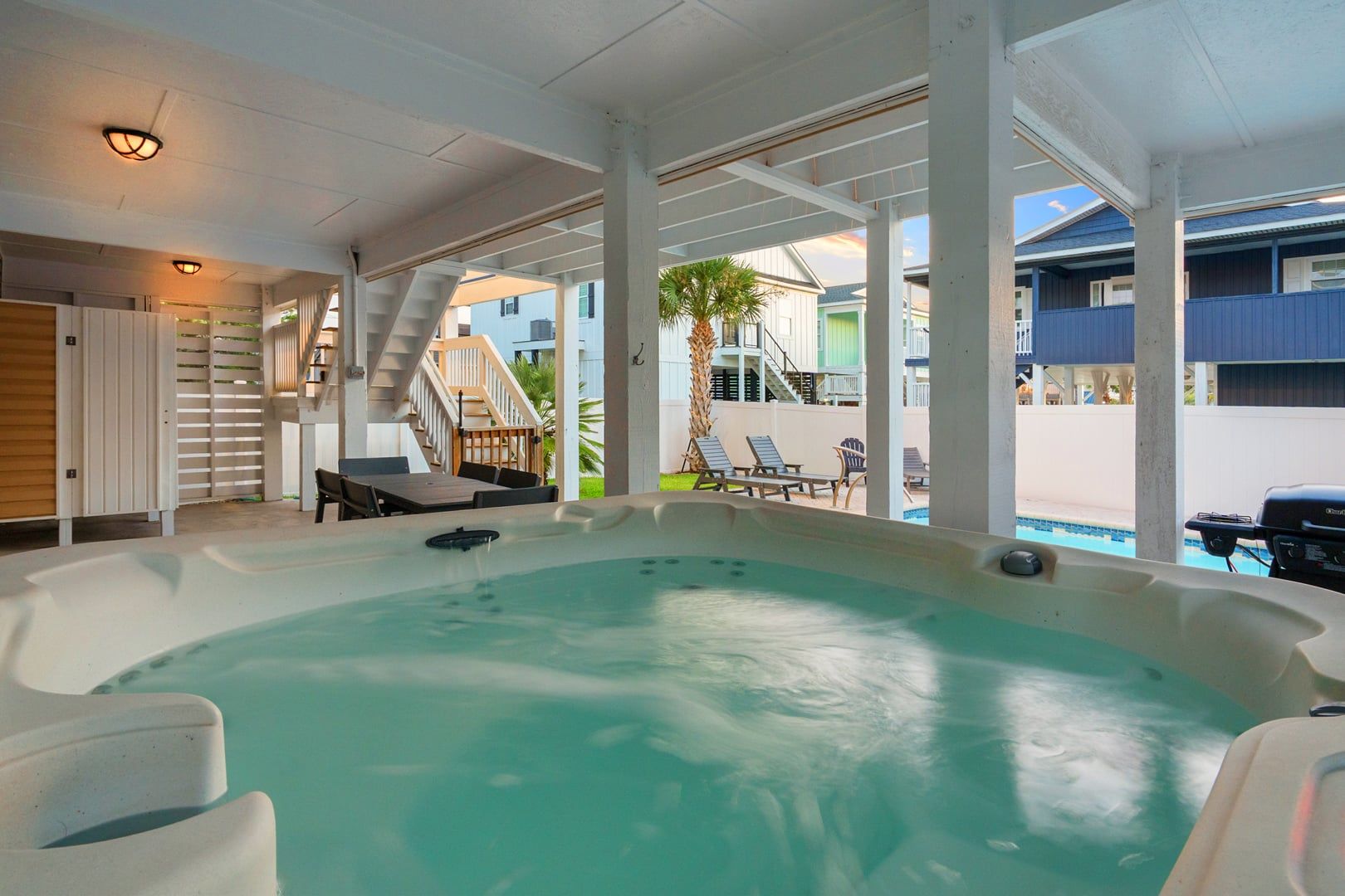 Un espace avec un jacuzzi et une piscine, des sièges extérieurs et un escalier menant à une terrasse.