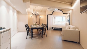 A modern, well-lit dining area with a chandelier, a sofa, and a bed in the background. - MONTHLIV Euljiro Hotel Stay (Seoul)