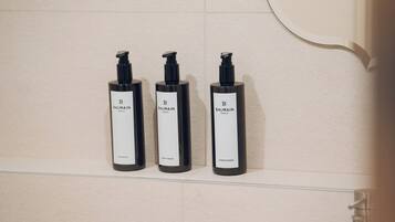 Tres botellas negras de Balmain Paris sobre un estante de baño.