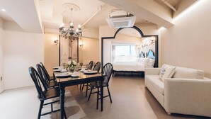 A modern living room with a dining area, featuring a chandelier, a sofa, and a large mirror. - MONTHLIV Euljiro Hotel Stay (Seoul)