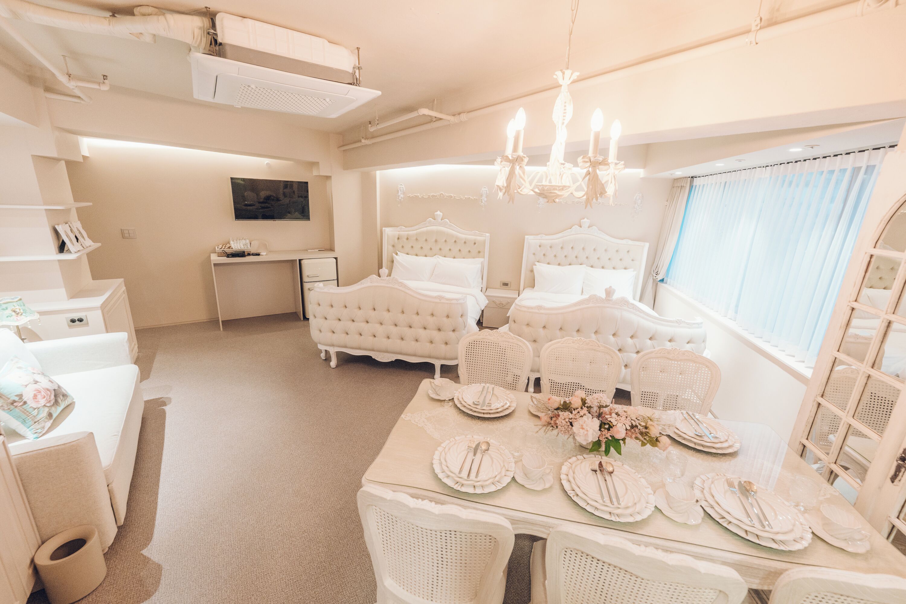 A hotel room with a large bed, a dining table set for four, and a TV in the corner.