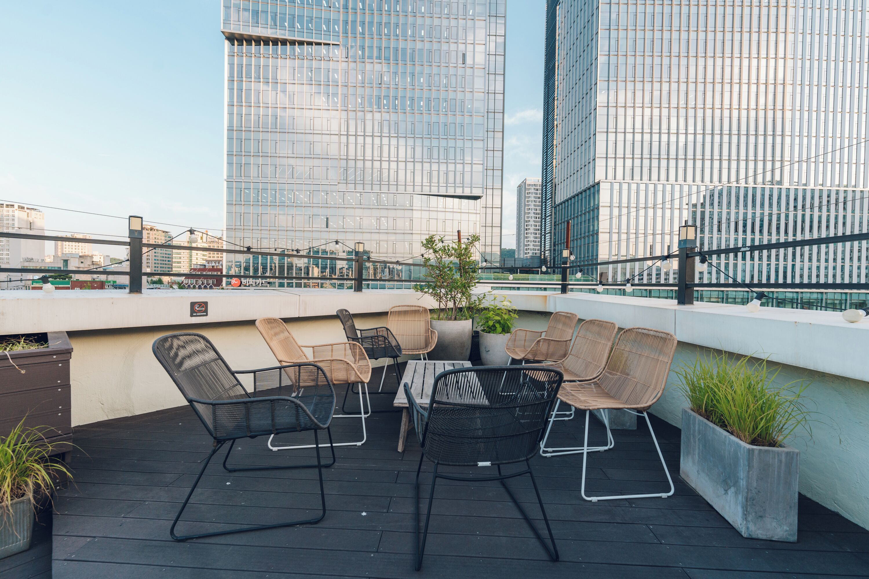 A rooftop terrace with outdoor seating, a table, and potted plants.