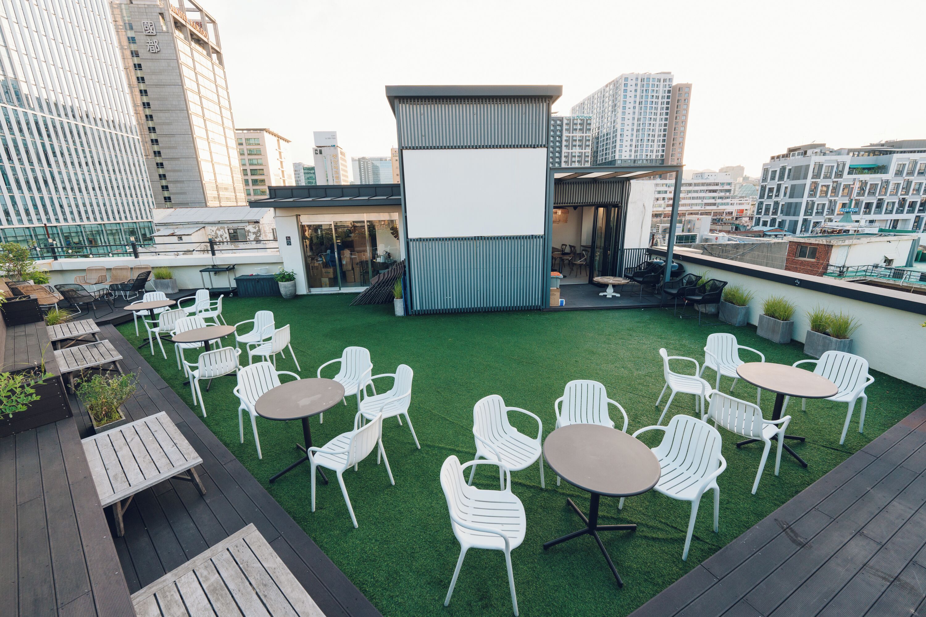 Terraza en la azotea con mobiliario exterior, una pantalla en blanco y vistas de la ciudad.