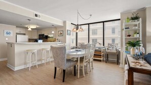 Une cuisine moderne dotée d’un îlot central, de tabourets de bar blancs et d’un coin repas avec une table ronde et des chaises.