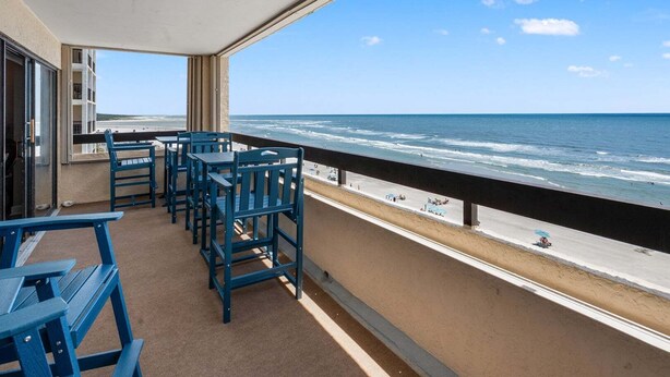 Un balcon avec vue sur l’océan, une table et des chaises.