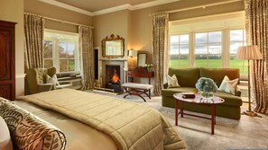 A spacious room with a large bed, a green sofa, a fireplace, and a view of the outdoors. - 5 Star Luttrellstown Castle - Dublin’s Timeless Luxury Awaits (Dublin)