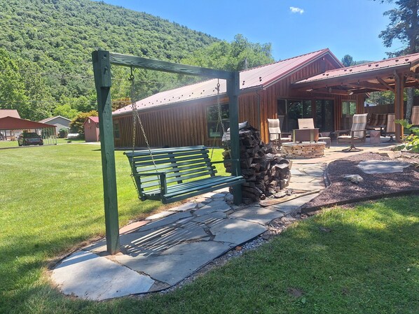Un banc en bois doté d’une structure métallique, un chemin pavé de pierres et un bâtiment rustique avec un toit rouge.