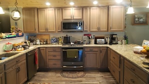 A kitchen with wooden cabinets, a microwave, stove, and granite countertops. - 50 minute ride to the Little League fields (cammal)