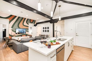 A modern kitchen with a central island, a dining area with a sofa, and a living room with a TV.
