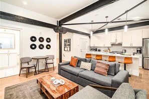 A modern living room with a grey sofa, coffee table, and dining area with chairs.