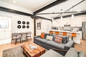 A modern living room with a grey sofa, coffee table, and dining area with chairs.