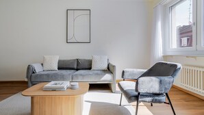 Un saló modern amb un sofà gris, un butaquesa gris, una taula de centre de fusta i una obra d'art abstracta emmarcada a la paret.