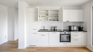 A modern kitchen with white cabinetry, a black countertop, and stainless steel appliances including a stove, oven, and coffee maker. - Blueground | Basel-Vorstaedte, view, nr Rhine (Basel)