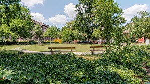A park with benches, trees, and a building in the background. - Blueground | Basel-Vorstaedte, view, nr Rhine (Basel)