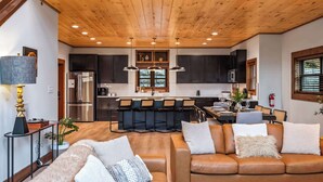 A modern kitchen with dark cabinets, stainless steel appliances, and a central island with bar stools. - Luxury Mountain Lodge | Huge Game Room | Htd Pool (Sevierville)