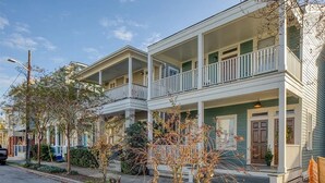A row of two-story houses with balconies, a street lamp, and a car parked on the side. - Stylish 1900s Renovated Apartments (Savannah)
