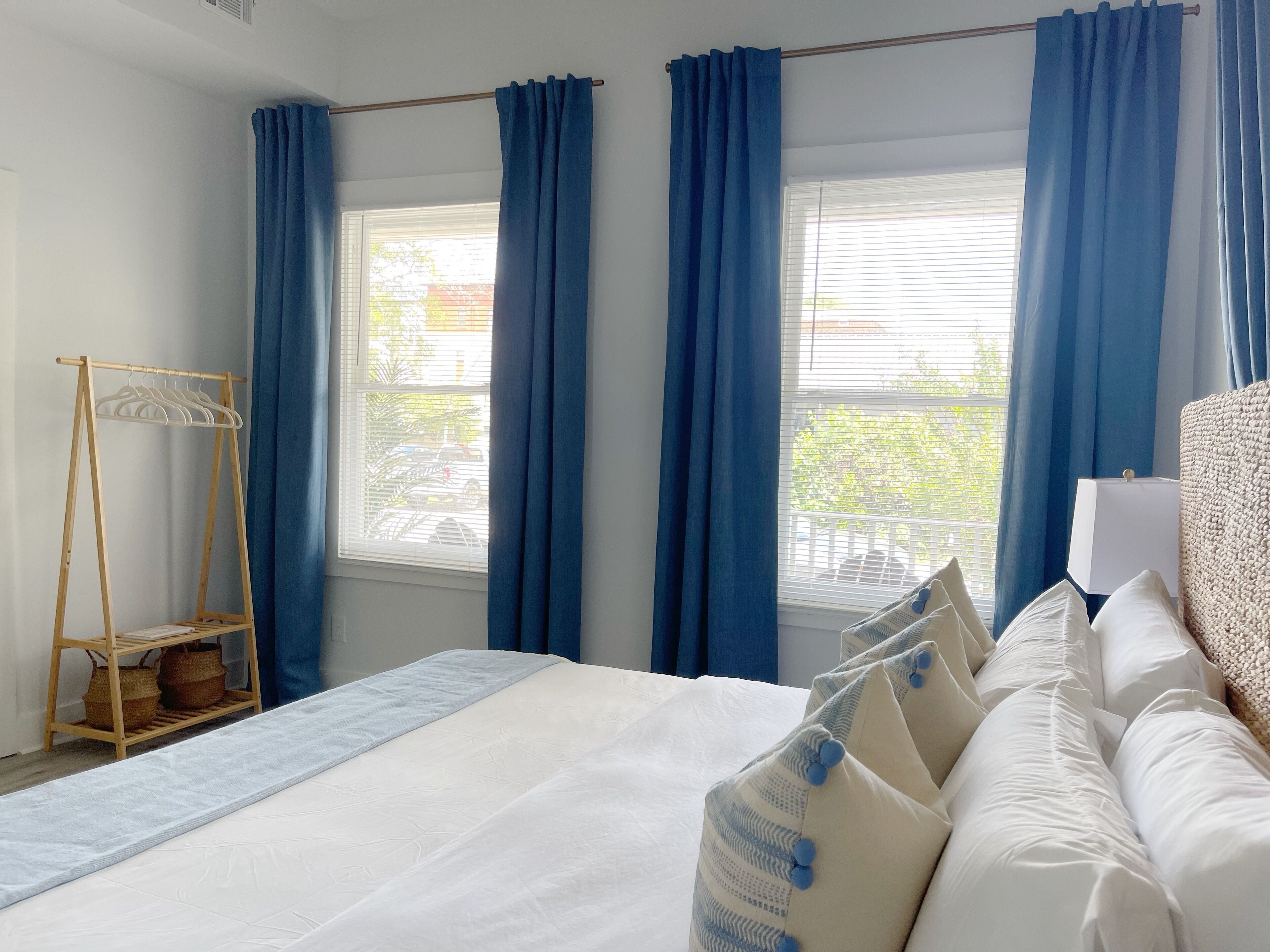 Una habitación de hotel con una cama, un armario de madera y una ventana con cortinas azules.