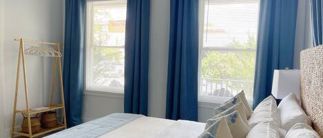 Una habitación de hotel con una cama, un armario de madera y una ventana con cortinas azules.