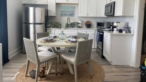A modern kitchen with white cabinets, a stainless steel refrigerator, a microwave, and a coffee machine. - Stylish 1900s Renovated Apartments (Savannah)