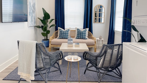 A modern living room with a sofa, two chairs, a coffee table, a potted plant, and a TV on the wall. - Stylish 1900s Renovated Apartments (Savannah)