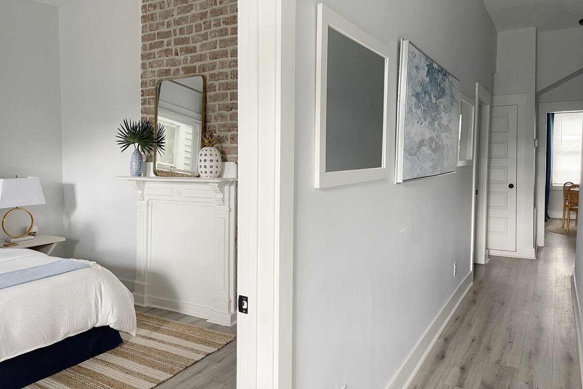 Une chambre à coucher avec un lit, une table de chevet, une lampe, un miroir et un mur en briques.