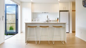 Una cocina moderna con una isla central, armarios blancos y suelo de madera.